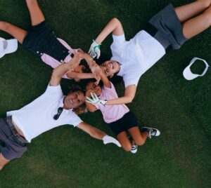 Joyful family in casual attire lying on grass, forming a heart shape with their hands.