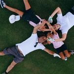 Joyful family in casual attire lying on grass, forming a heart shape with their hands.